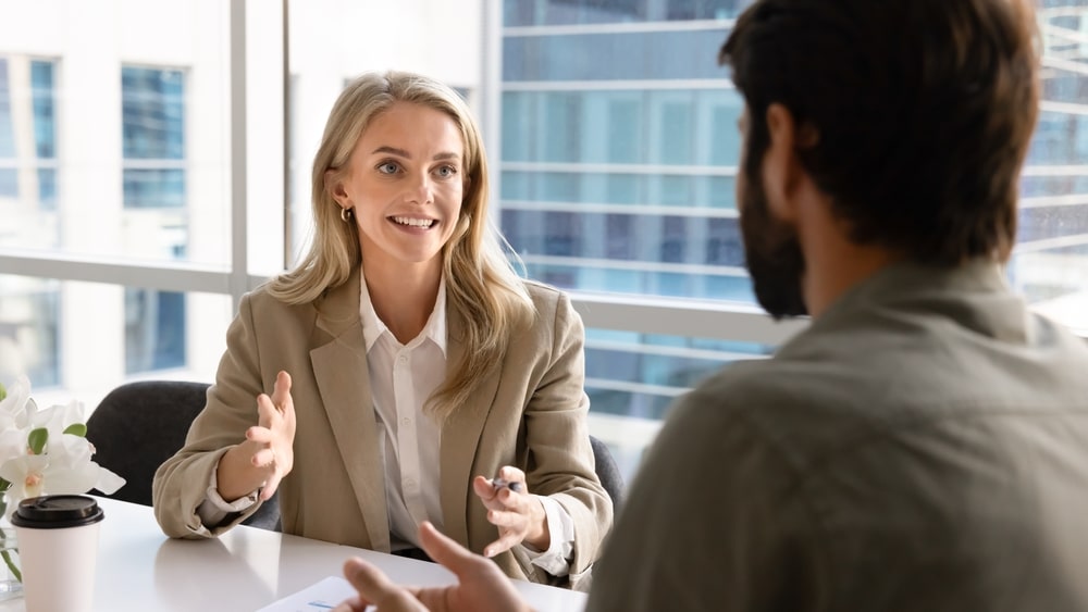Happy,Blonde,Young,Businesswoman,Talking,To,Business,Partner,At,Office
